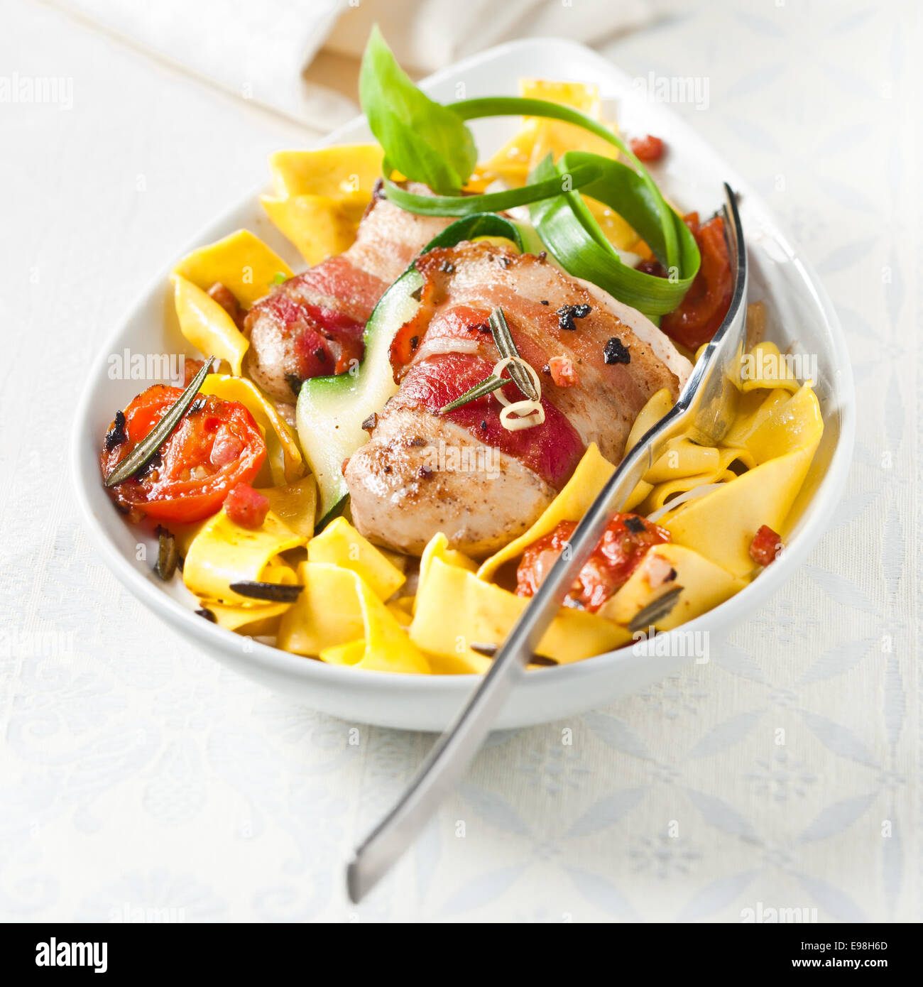 Traditional wide Italian pappardelle egg noodles with bacon, tomato