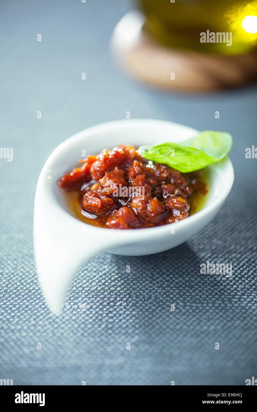 Tasty spicy piquant Italian tomato based sauce or dip served in an elegant bowl topped with a fresh basil leaf Stock Photo