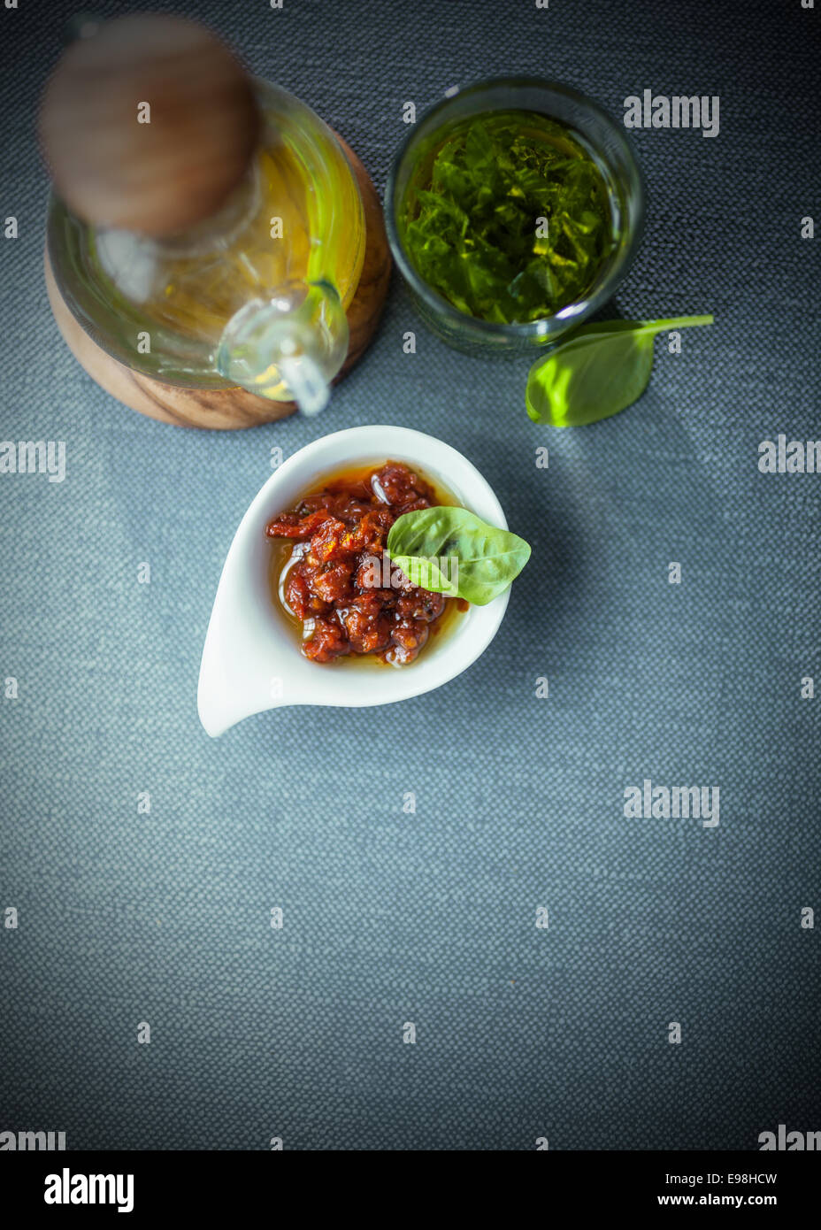 Savory condiments in a restaurant with a spicy dip, virgen olive oil in a decanter and fresh basil pesto, overhead view with copyspace Stock Photo