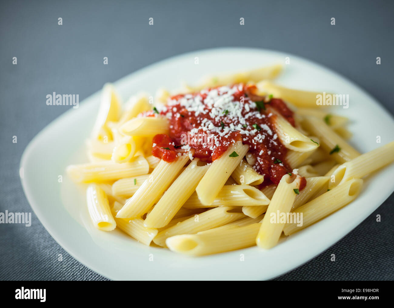 Serving of traditional cooked penne rigate pasta topped with a spicy