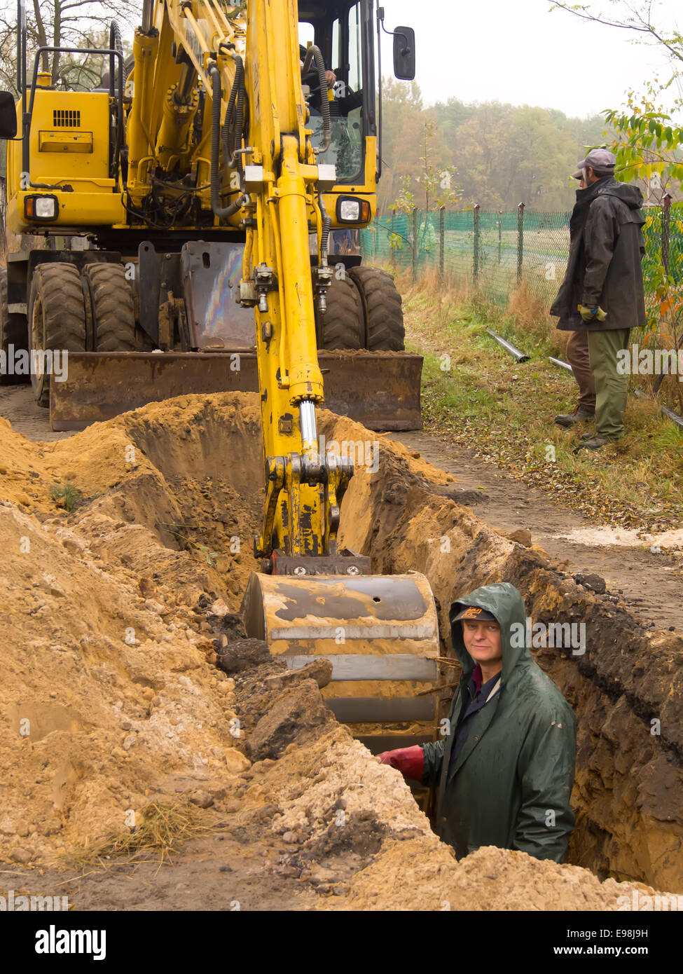 Workers are digging a deep hole with digger Stock Photo