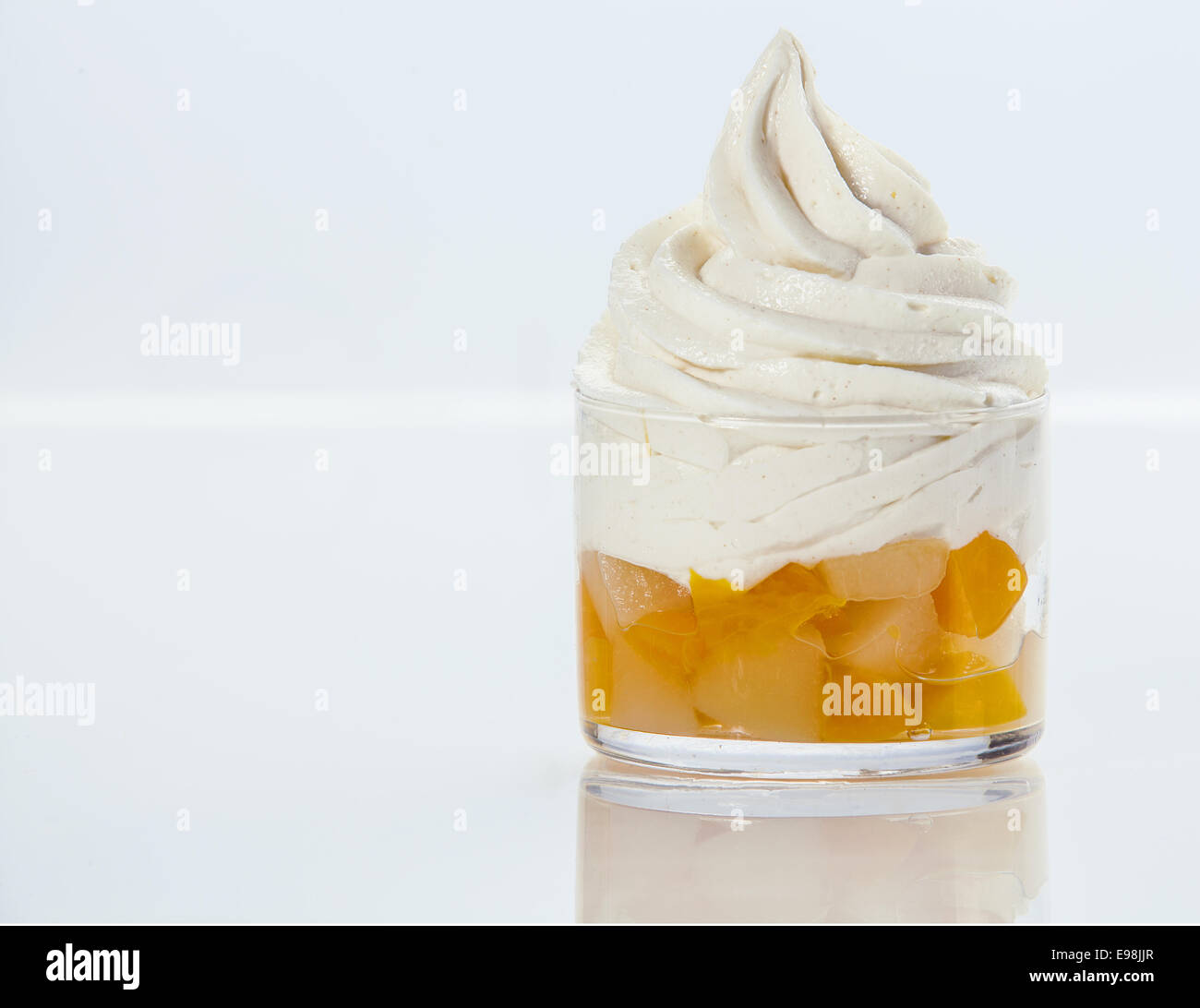 Fresh fruit salad topped with a swirl of healthy low-fat frozen yogurt served in a glass dish on white with copyspace Stock Photo