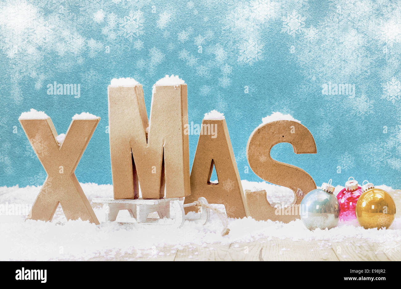 Cold wintry Xmas background with wooden letters for Xmas in snow with colorful Christmas baubles under falling snowflakes on a cool blue background with copyspace Stock Photo