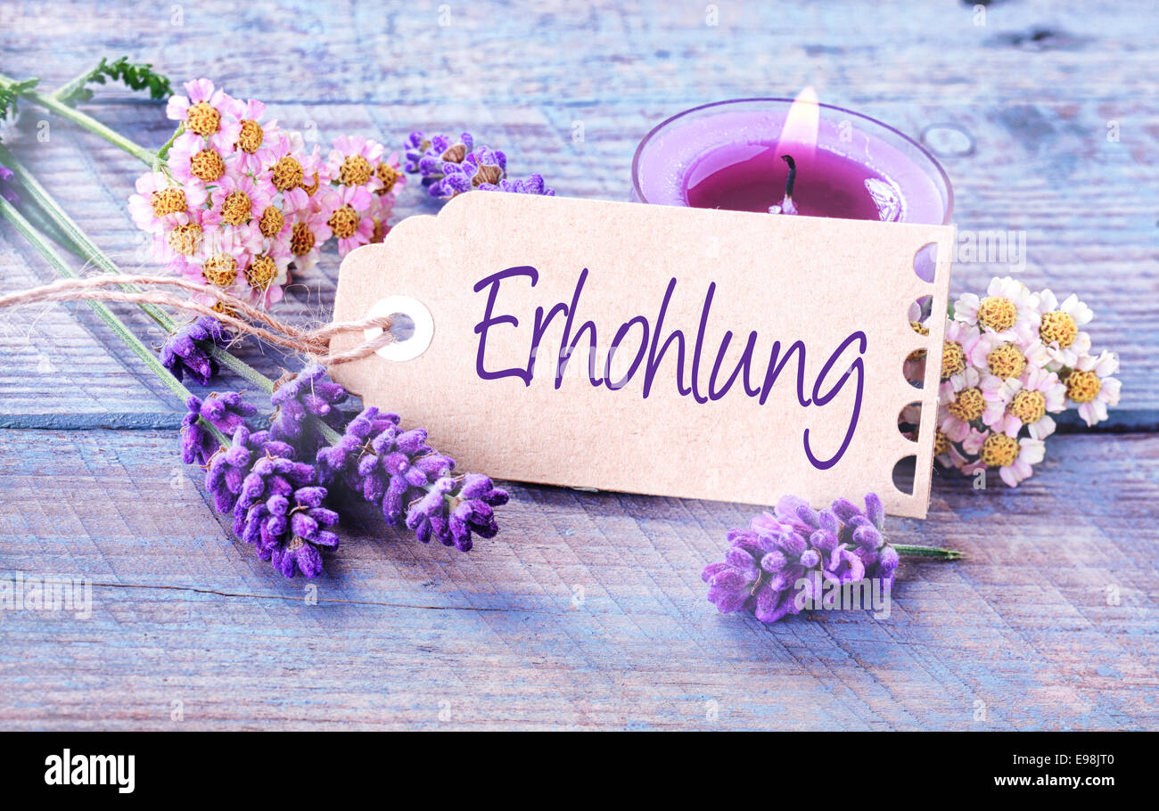 Ehrhohlung - revitalization and wellness background with a handwritten label with the word - Ehrhohlung - in German with a burning aromatherapy candle and fresh lavender on lilac colored wooden boards Stock Photo