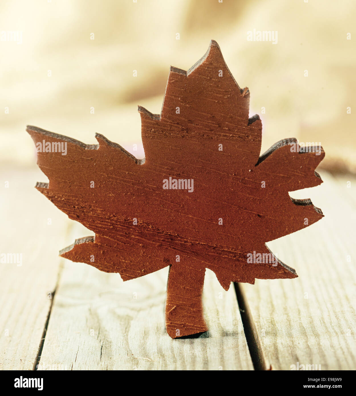 Rustic wooden Xmas maple leaf handicraft cut out decoration on an old weathered wooden table with textured background, square format Stock Photo