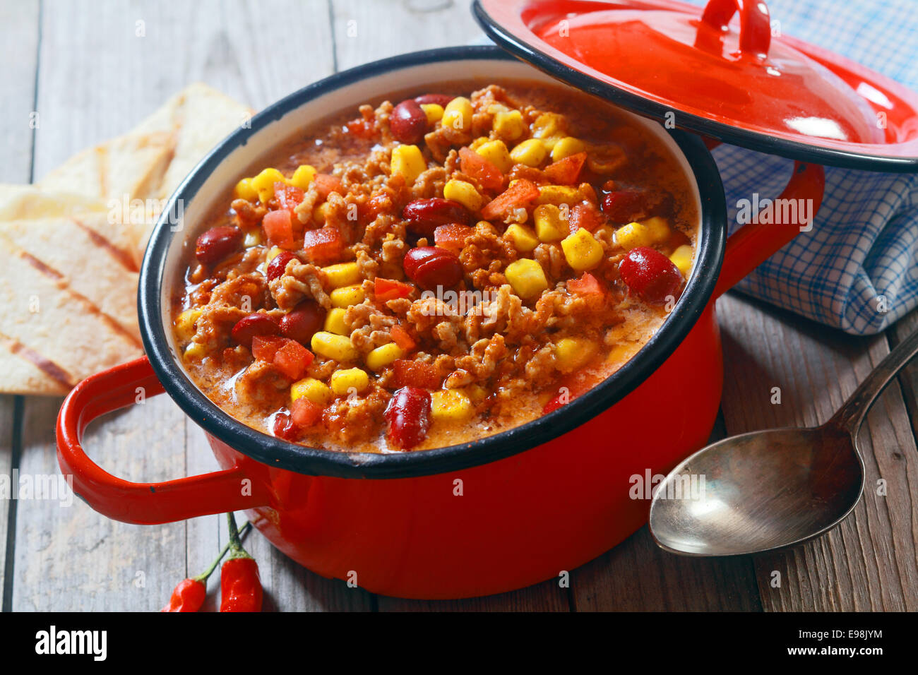 Close up Appetizing Healthy Meaty Dish on Red Pot with Serving Spoon on Side. Placed on Wooden Table. Stock Photo
