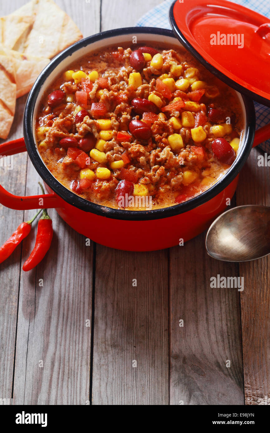 Mouth Watering Hot Meaty Dish on Red Pot Placed on Wooden Table Ready to Eat. Stock Photo