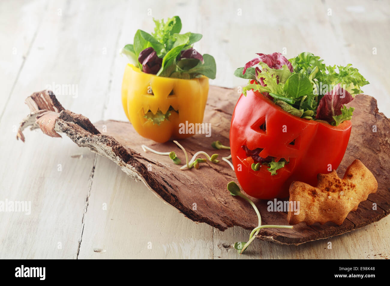Colorful fresh Halloween bell pepper salads in individual servings for appetizers with carved jack-o-lantern faces stuffed with Stock Photo