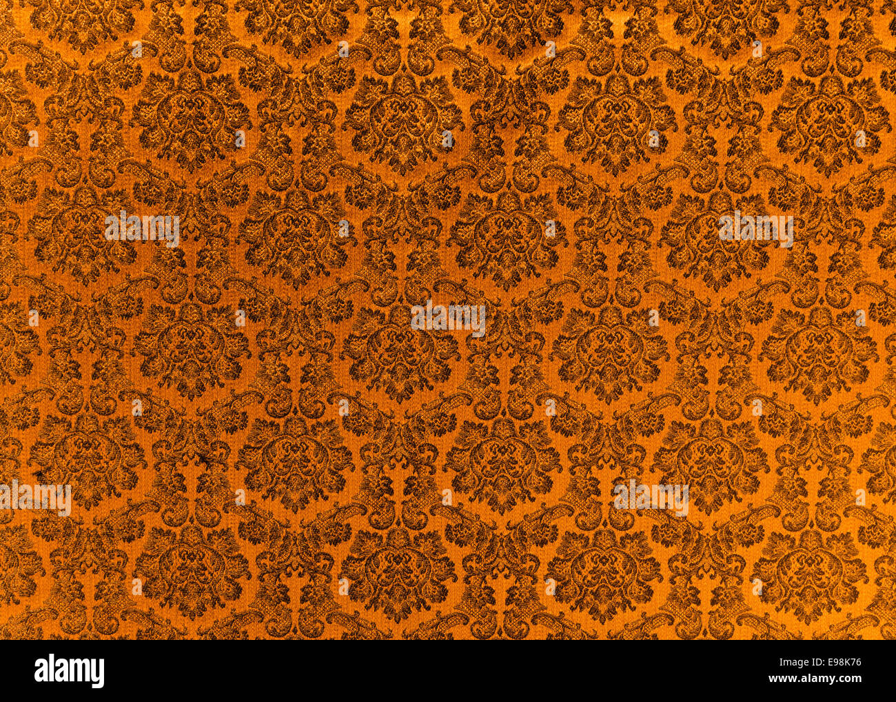 Abstract background of a heavy copper brocade fabric with interwoven repeat design. Stock Photo