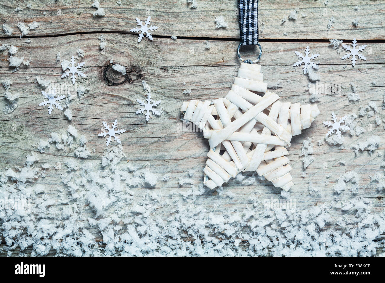 Country style Christmas star wound with white tape hanging on an old wooden background with falling snowflake decorations and winter snow Stock Photo