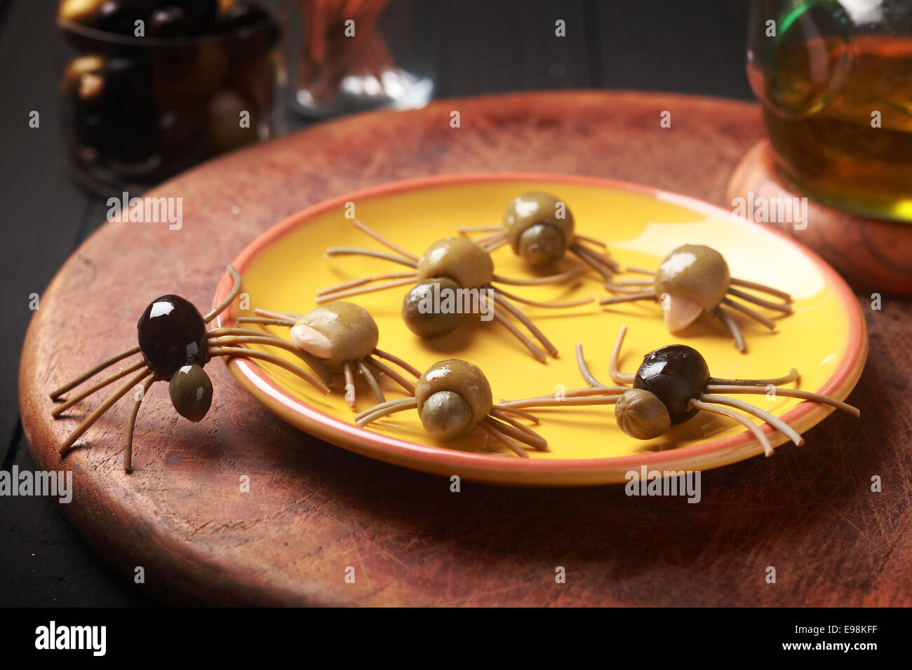 Creepy crawly edible Halloween spiders made from cured green and black olives with Italian spaghetti legs on a side table at a Halloween party for appetizers or favors for trick-ot-treating Stock Photo