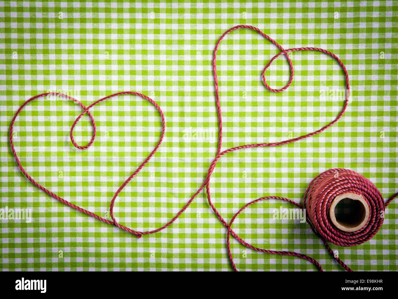 Hearts drawn with purple thread through a tag over a checkered fabric pattern Stock Photo