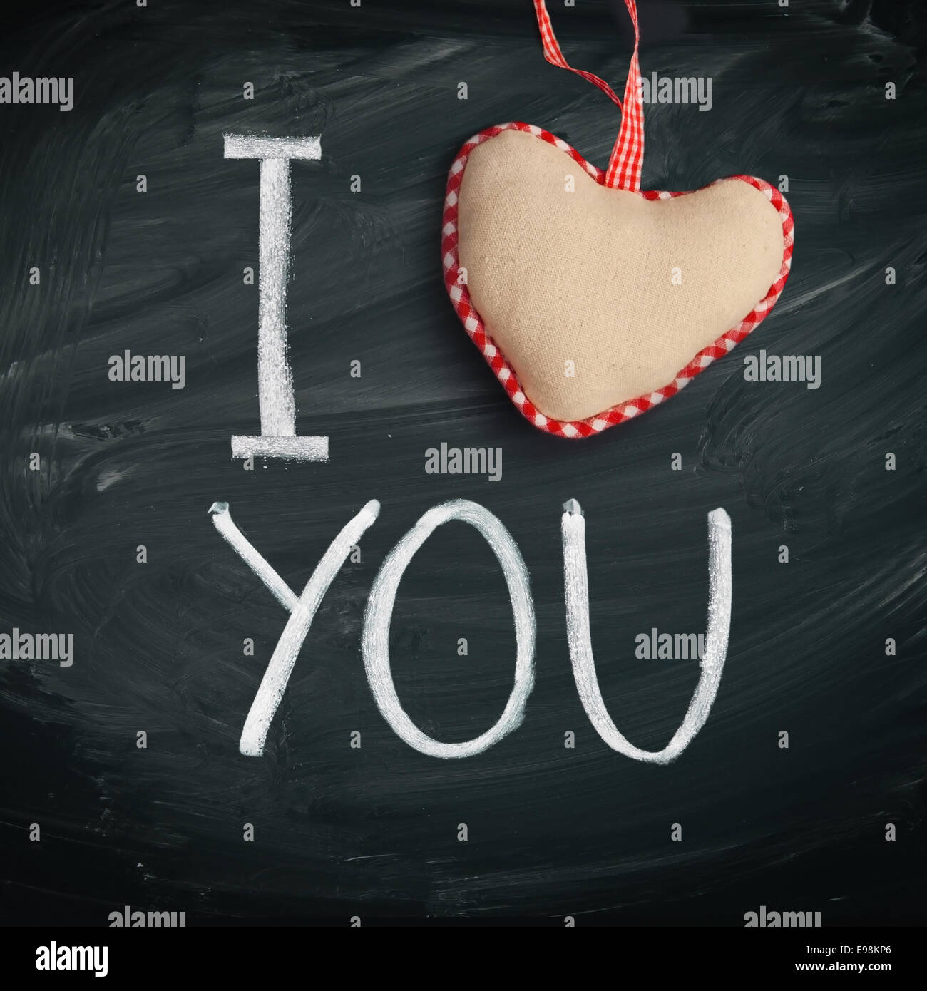 I Love You. Handwritten message on a chalkboard with a rustic needlework heart used as a symbol of love in this Valentines message. Stock Photo