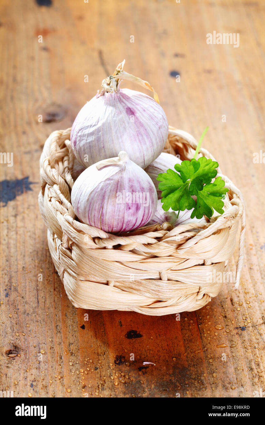Garlic in a box with parsley on a rustic wooden board Stock Photo