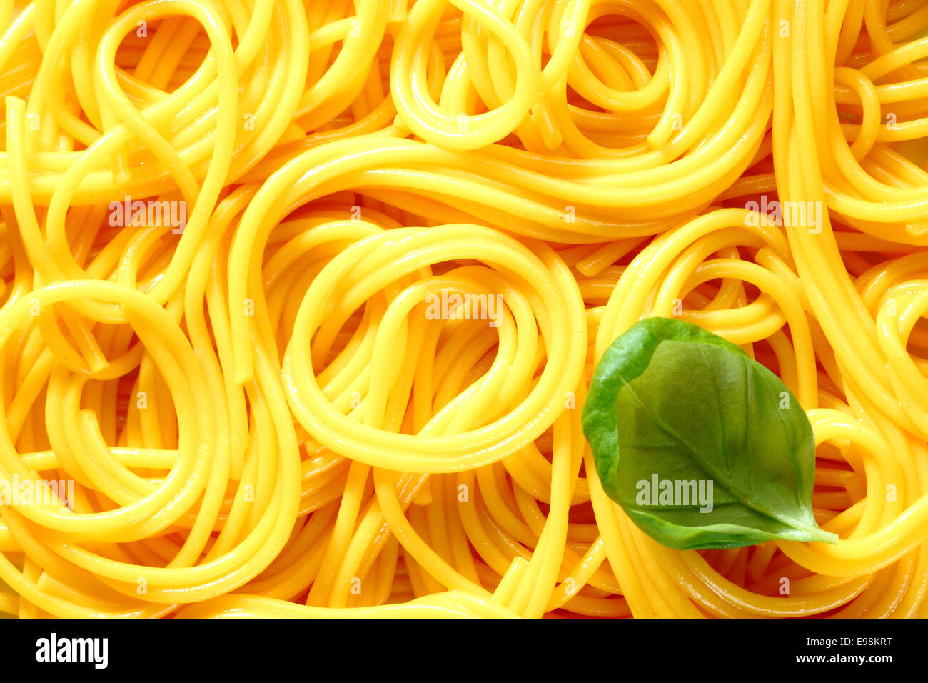 Closeup of freshly boiled spaghetti coiled in random patterns for an interesting background. With basil Stock Photo