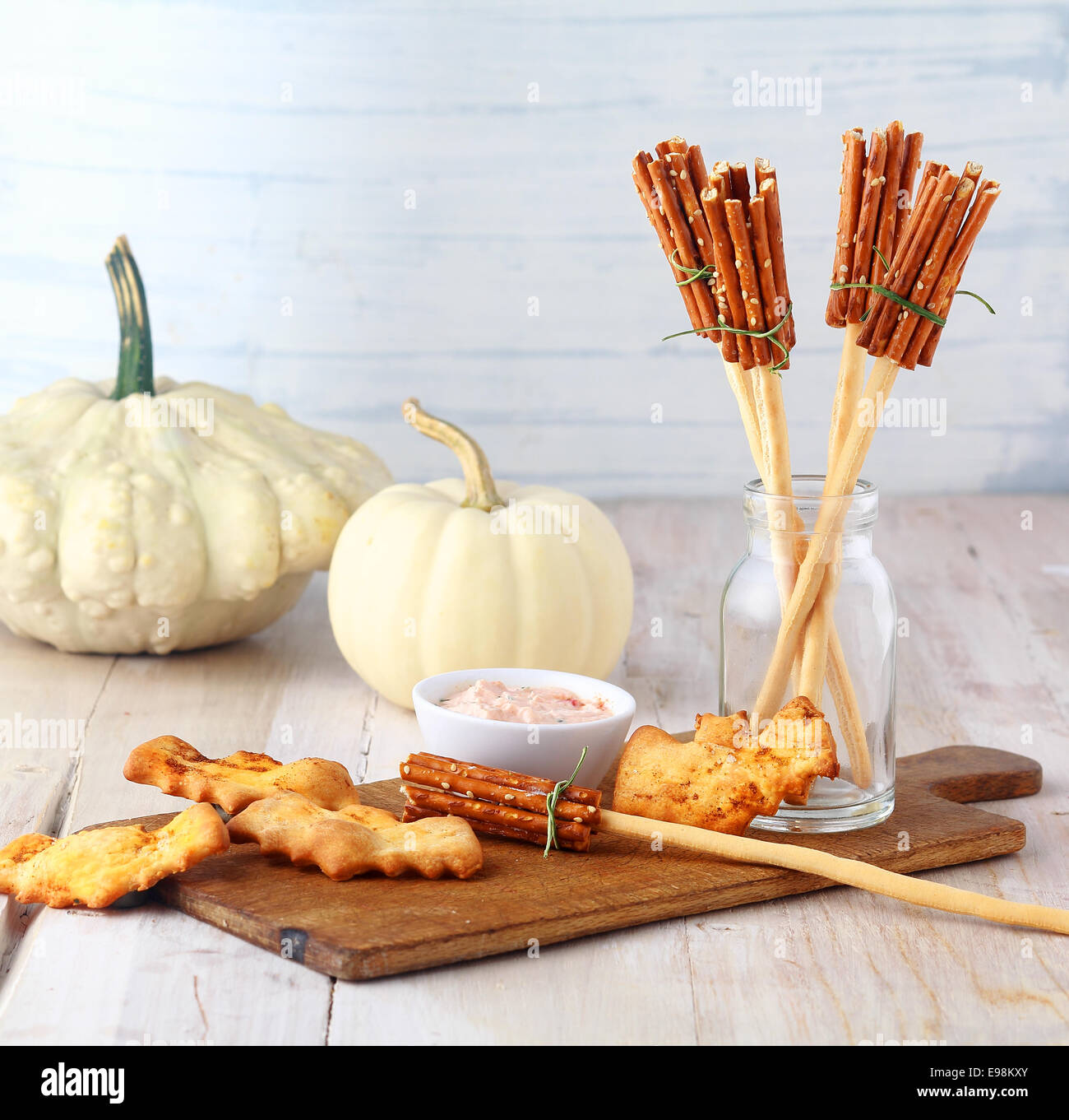 Fun homemade rustic Halloween witches broomstick appetizers made from bread sticks and pretzels served on a wooden board with a Stock Photo