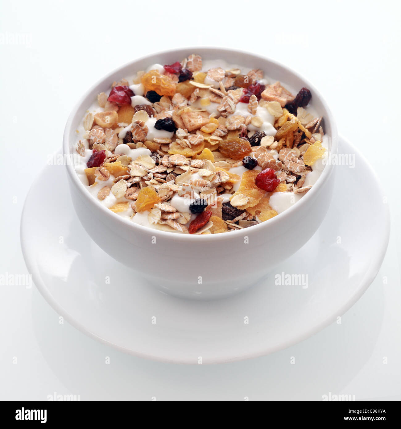 Bowl of delicious breakfast muesli with oat and wheat flakes mixed with dried fruit and nuts served in a white ceramic bowl for Stock Photo