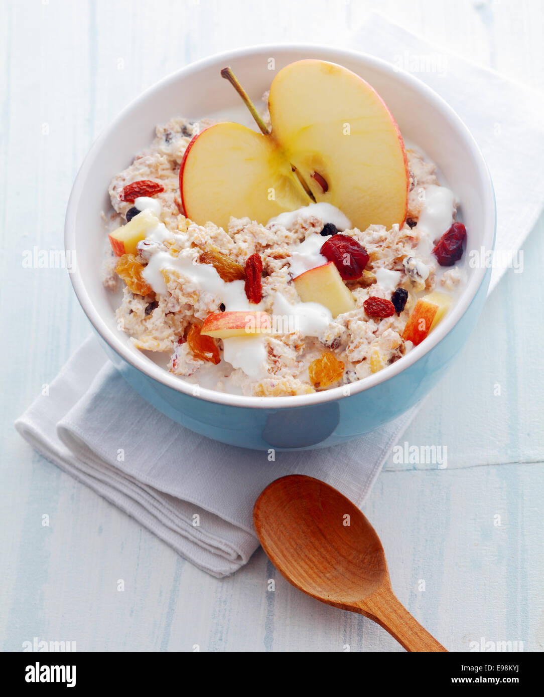 Delicious homemade muesli with fruit including fresh halved and diced apple and dried apricots and raisins and nuts served in a Stock Photo