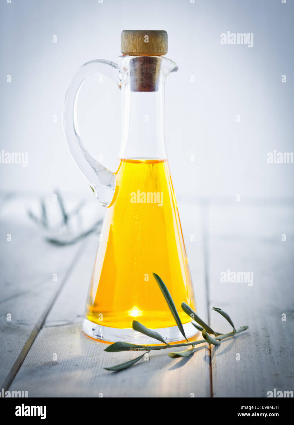 Olive Oil Carafe with herbs and a vignette, standing on a wooden white plate, for italian kitchen. Stock Photo