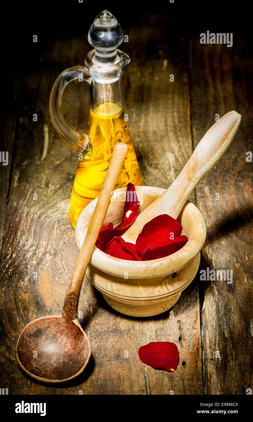 Wellness Care Treatment with rose leaves and ethereal oil on a wooden plate. Stock Photo