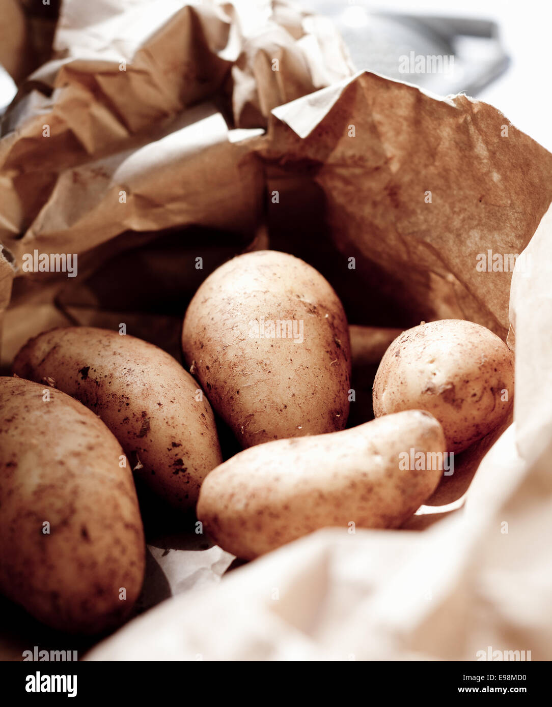 Closeup of fresh unwashed potatoes for sale at market in a recyclable brown paper bag Stock Photo