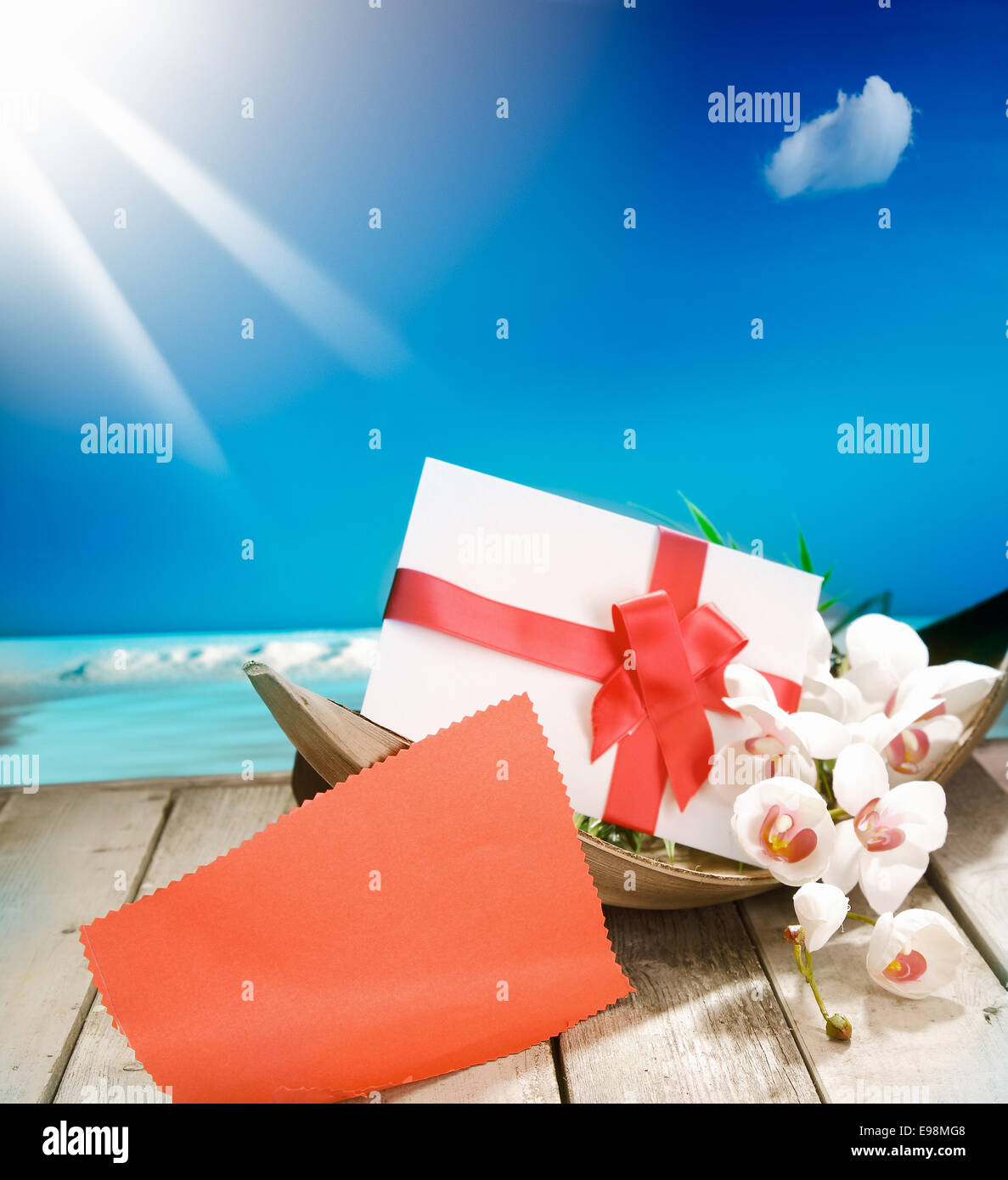 Voucher in a palm bowl with a bow at a deck in front of the deep blue pacific ocean and a shiny sun. With copyspace for your own Text and messages Stock Photo