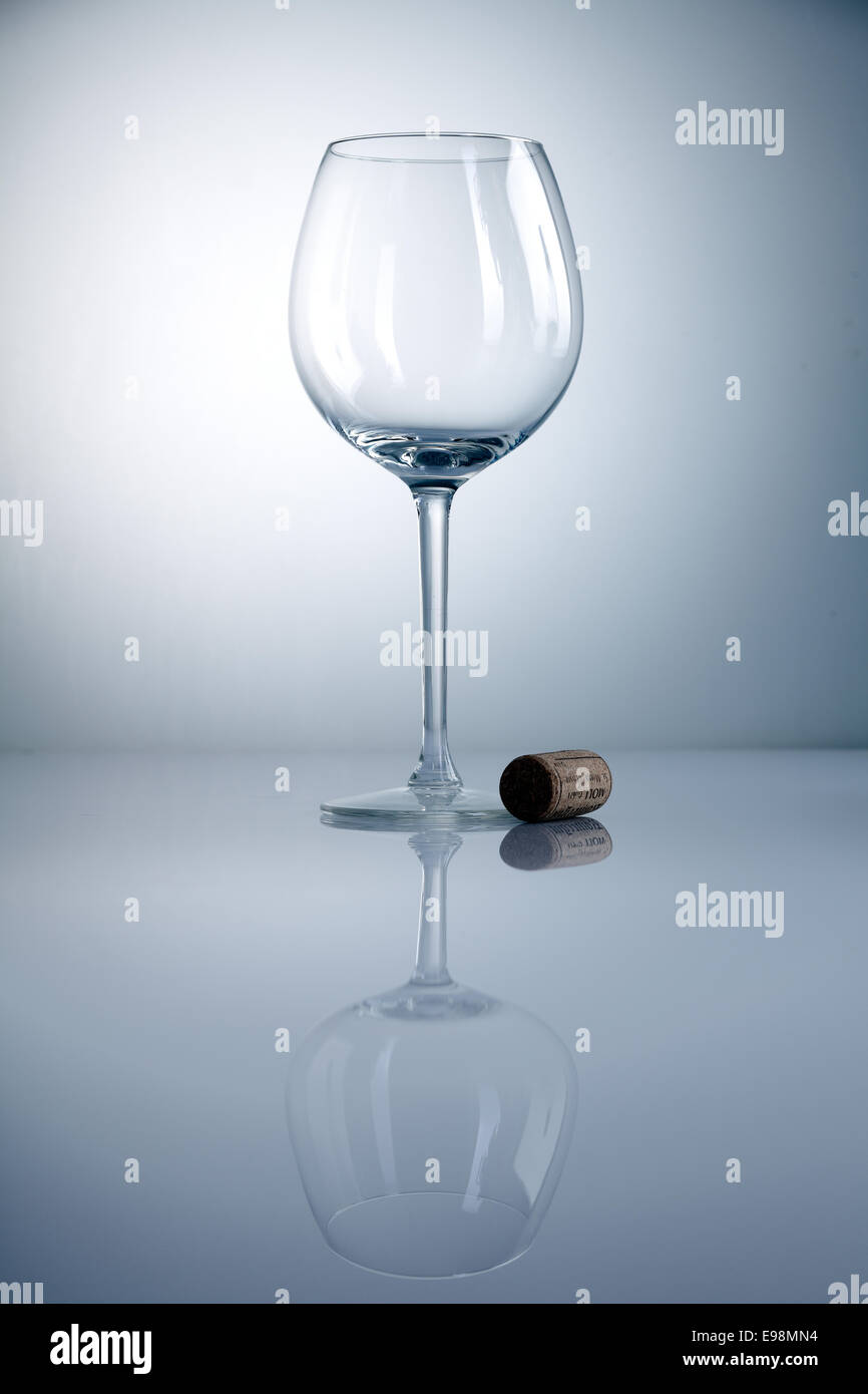 Empty wine glass with cork and reflexion on a blue background Stock Photo
