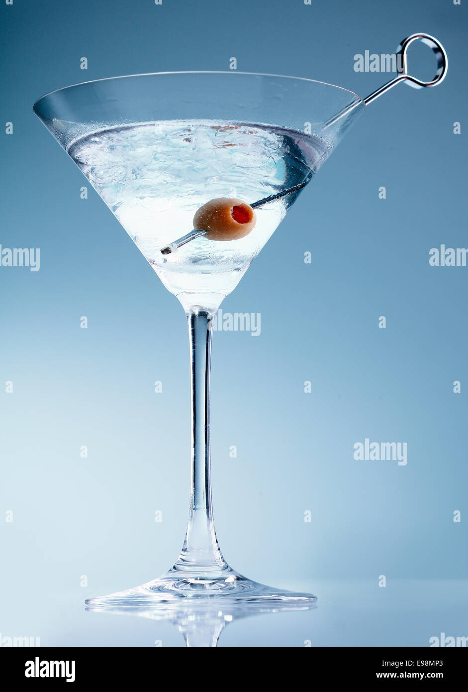 Shaken martini cocktail in a conical glass with an olive on a suffused