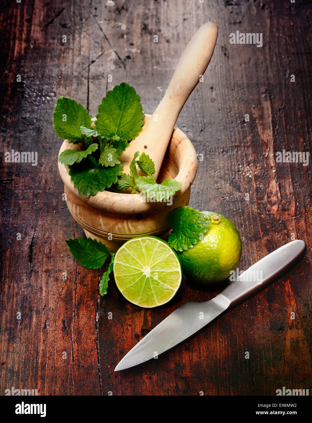 Mortar, Limes and Peppermint on a wood Background. Ingredients for Caipirinha and Mojito Cocktails and other drinks Stock Photo