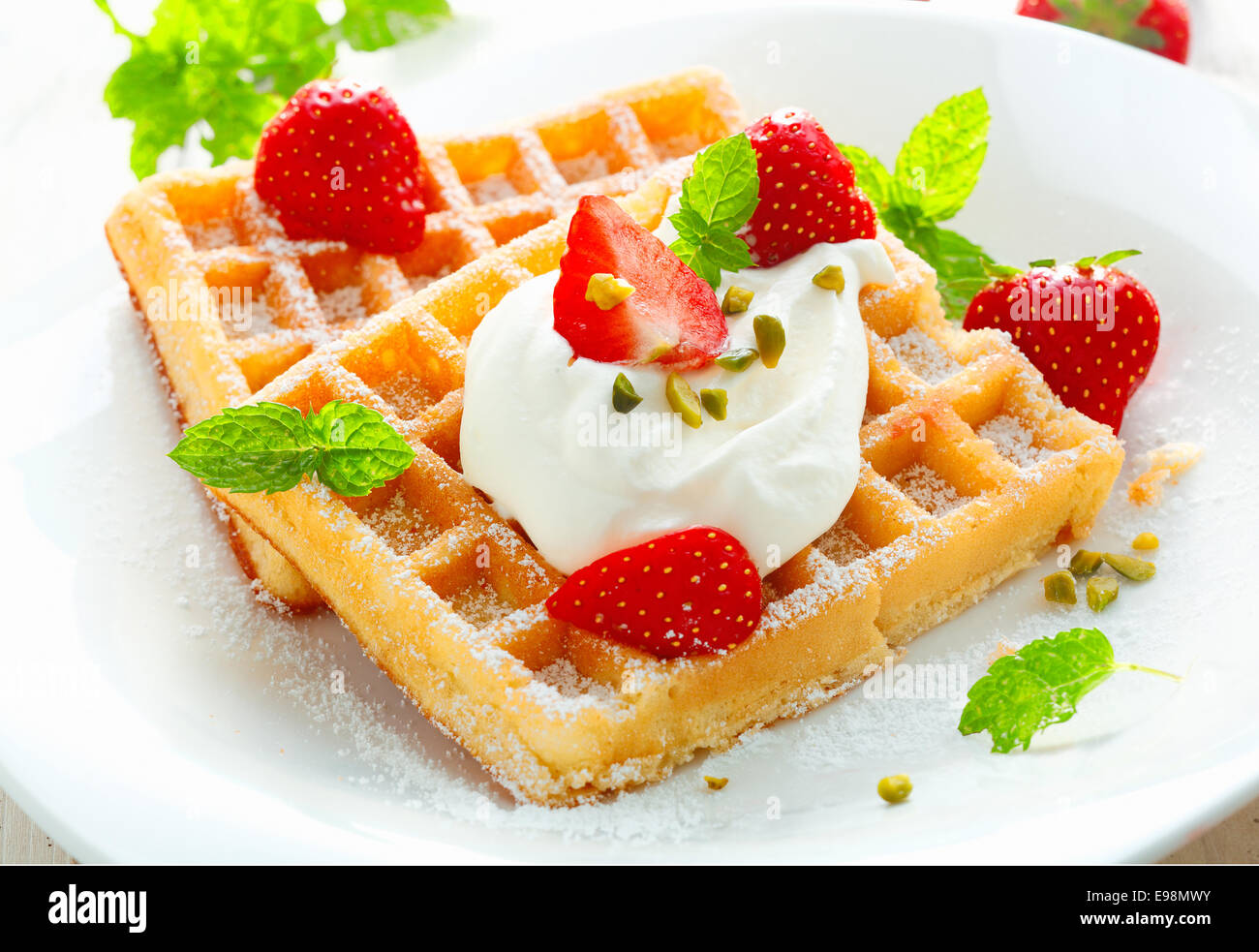 Golden waffle topped with fresh sliced strawberries and cream and ...