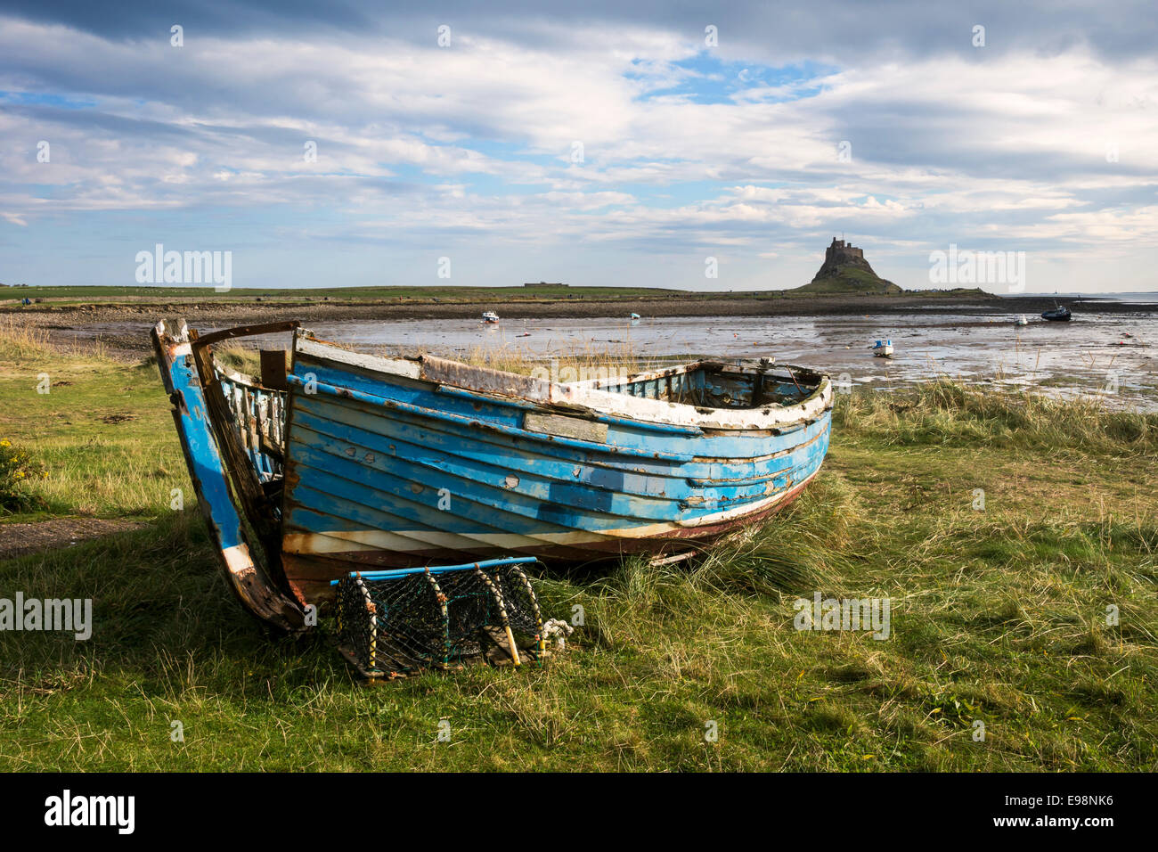 Old boat on Holy Island. Lindisfarne Castle and Harbour in the background Stock Photo