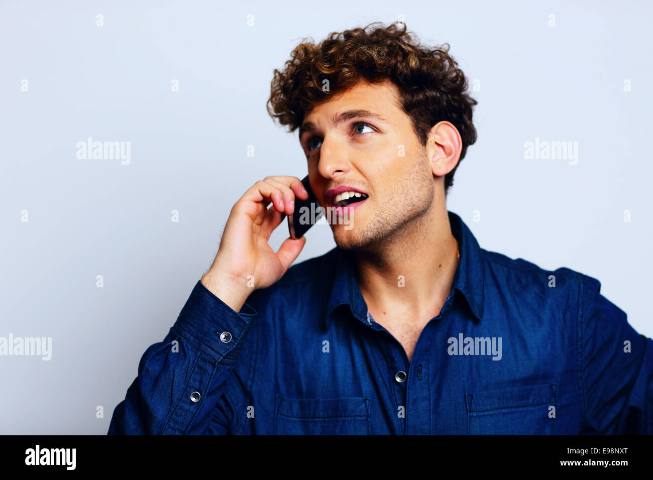 Man talking on a mobile phone and looking shocked Stock Photo