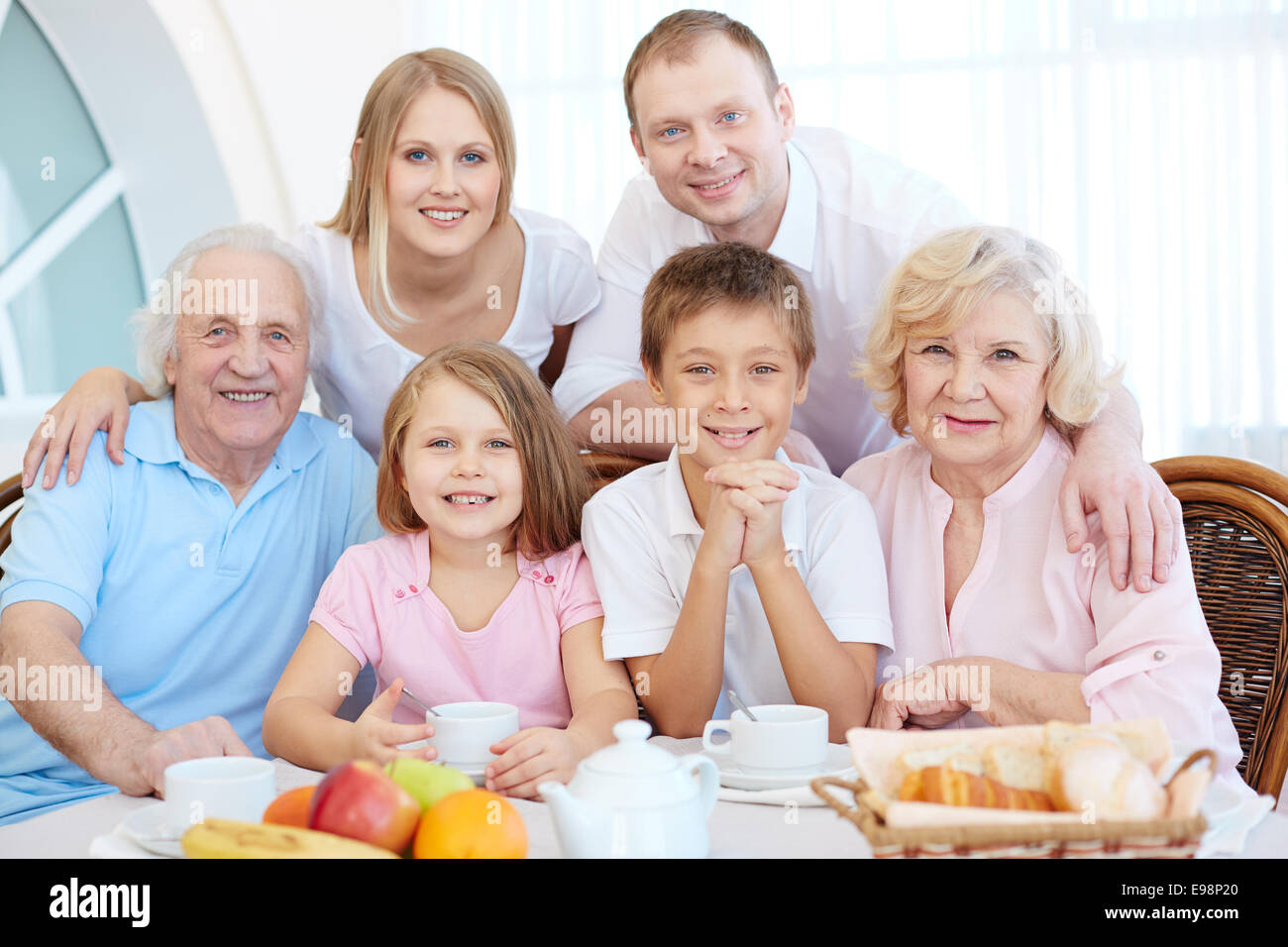 Portrait of happy senior and young couples and their children sitting by dinner table Stock Photo
