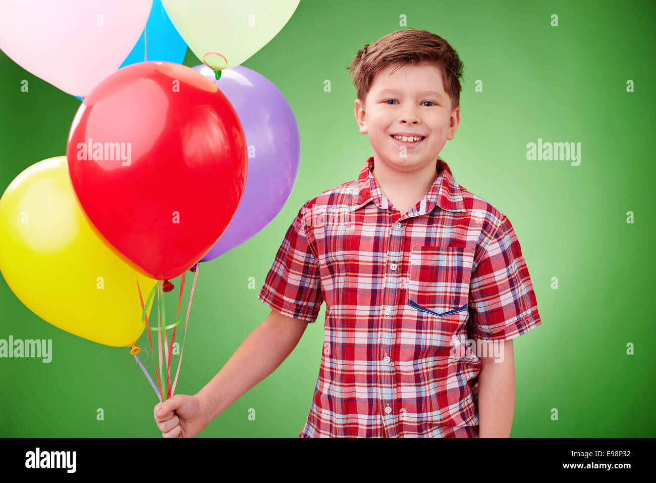 Smiling lad with balloons looking at camera in isolation Stock Photo