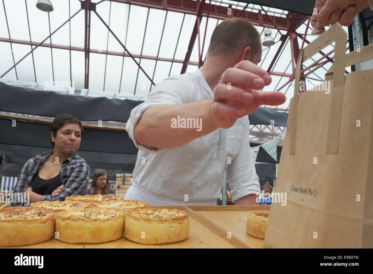 Another satisfied customer: Traditional pie maker serves a customer at the sunday Farmers' in Altrincham, Cheshire, UK Stock Photo