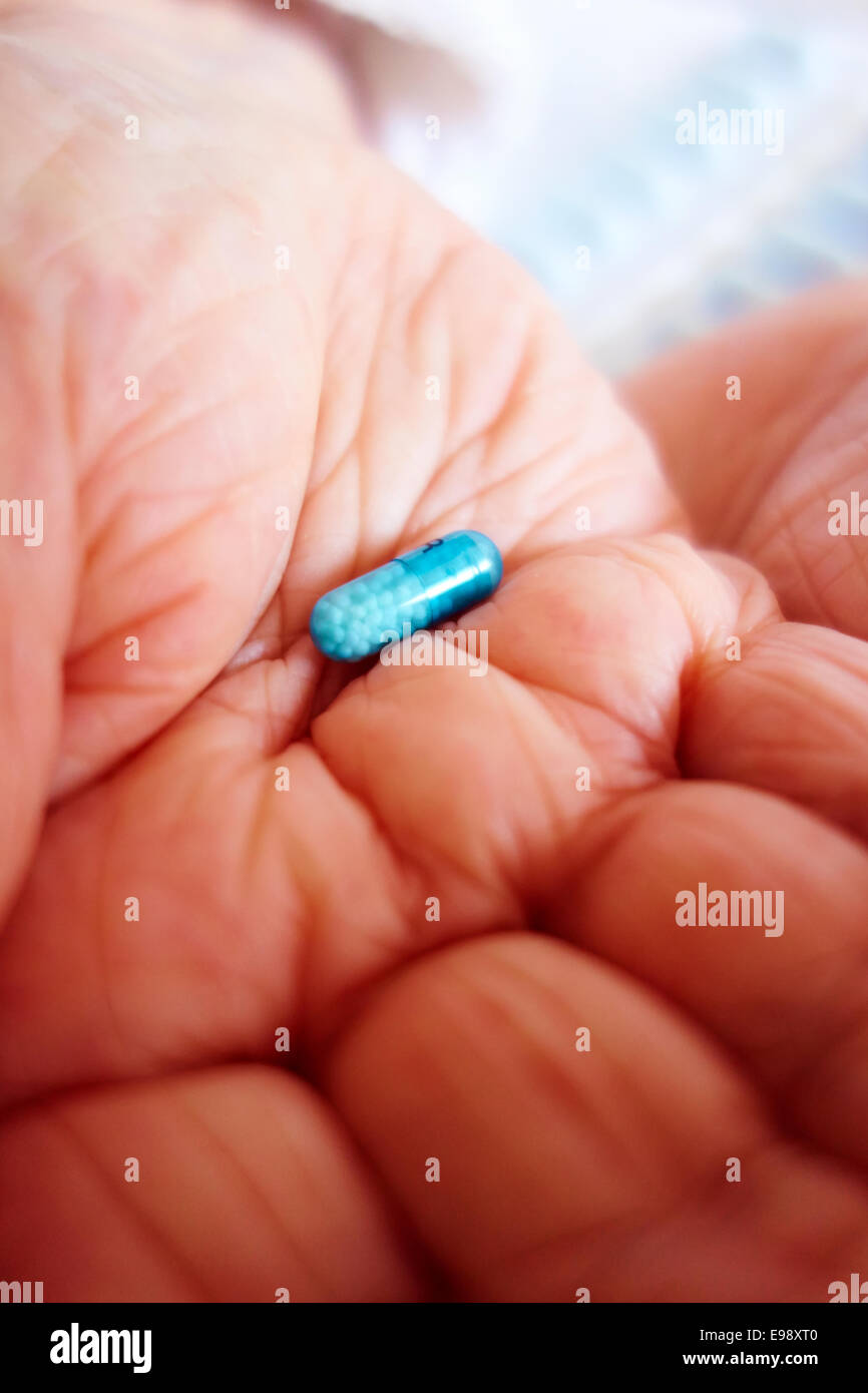 Senior person's hands holding a blue Bedranol propranolol hydrochloride pill / tablet /capsule prescription beta blocker medication - social care. Stock Photo
