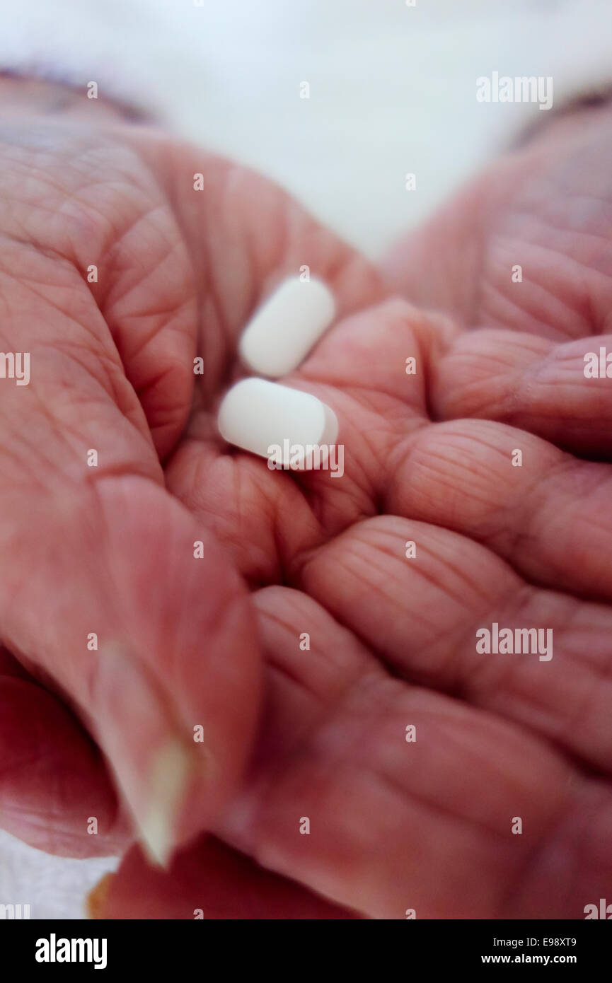 Senior person's hands holding white pill / tablet prescription medication - social care. Stock Photo
