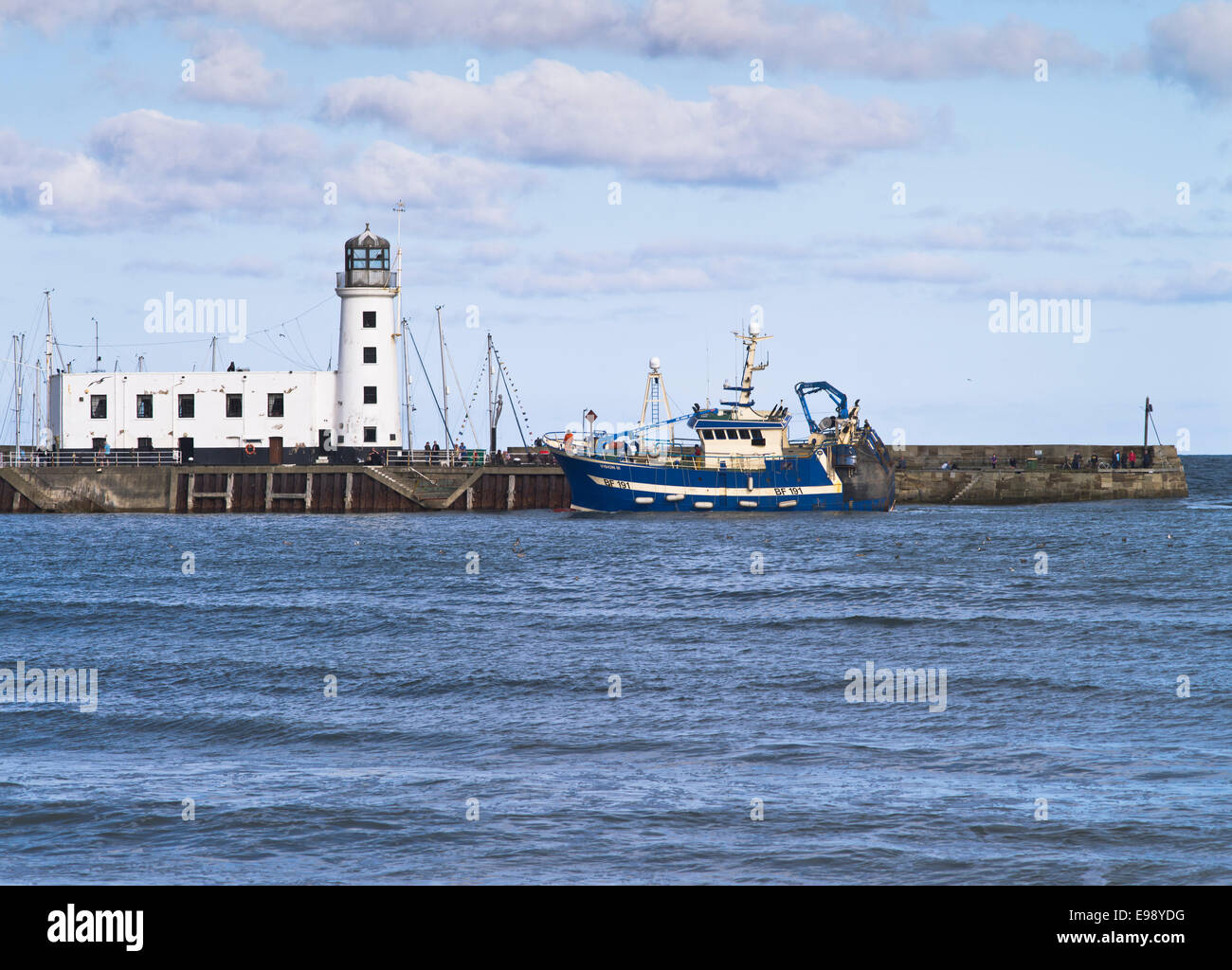 dh Scarborough Harbour SCARBOROUGH NORTH YORKSHIRE Lighthouse and fishing boat entering harbour pier uk Stock Photo