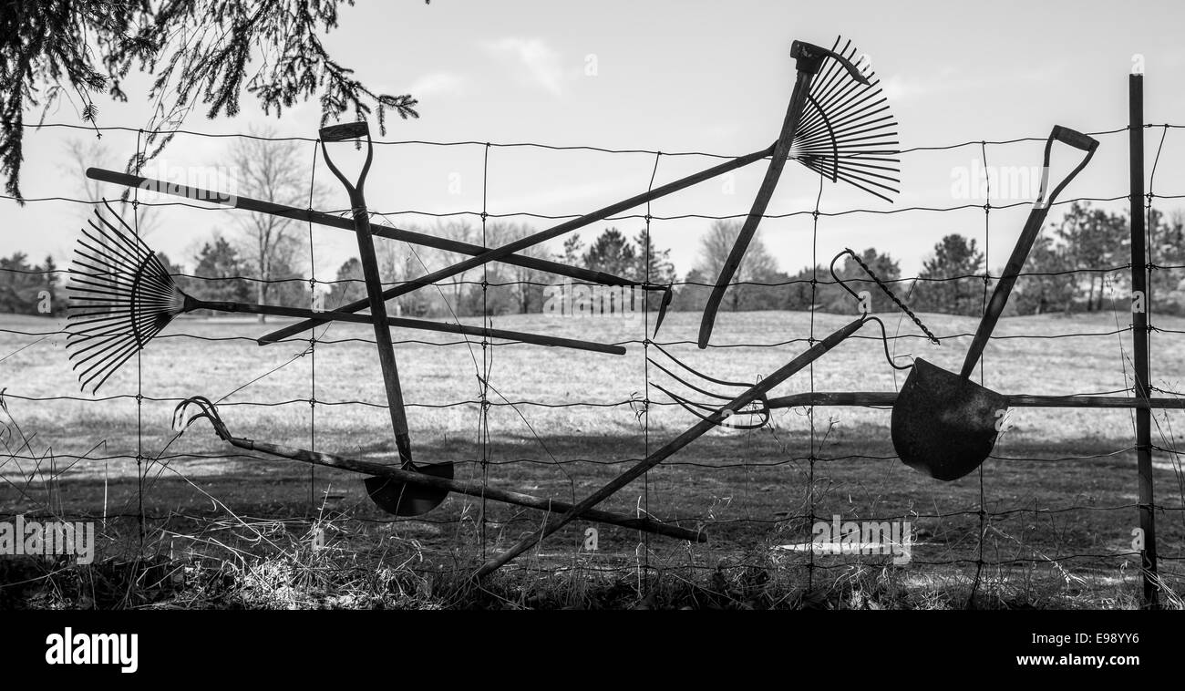 Various garden tools hang on a wire fence. Stock Photo