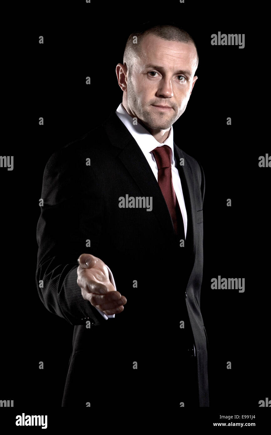 male fitness instructor with shaved head in a suit shot against a black background, Stock Photo