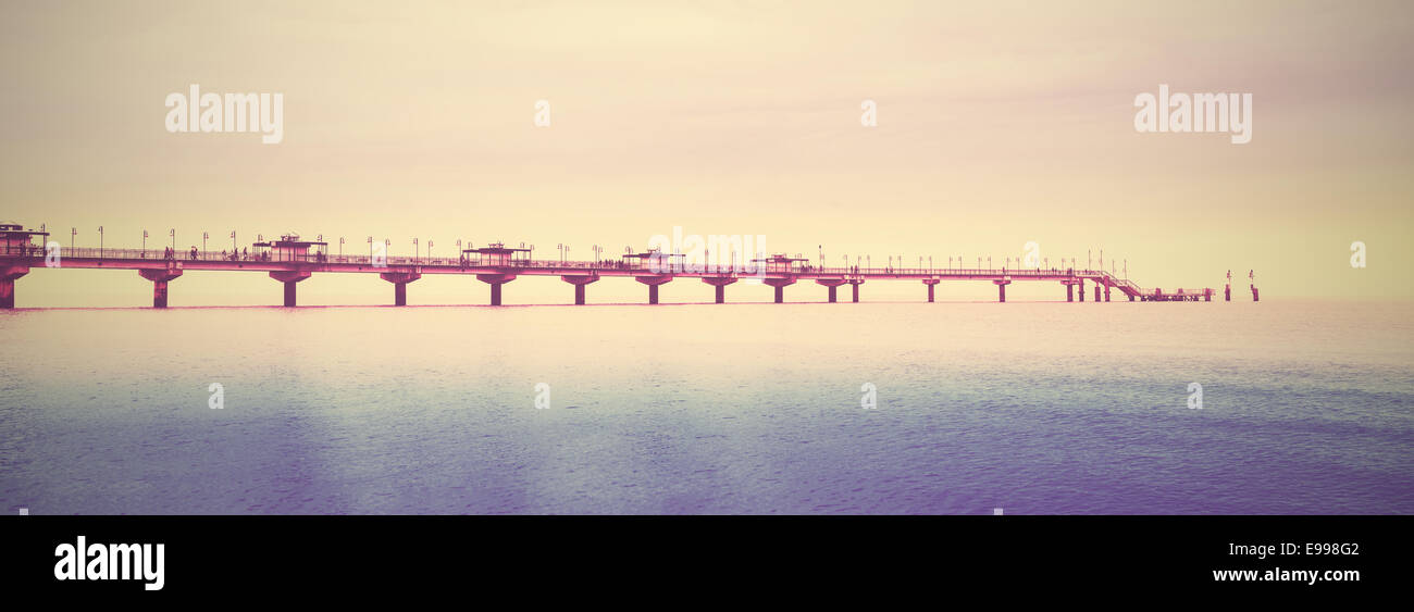 Retro filtered picture of long pier into the sea. Stock Photo