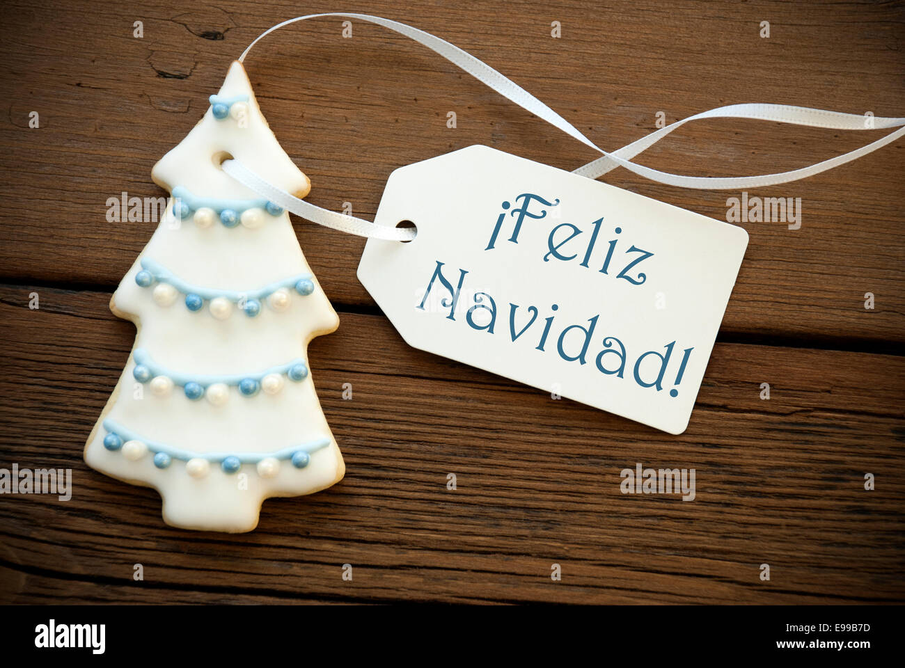 The Blue Spanish Words Feliz Navidad, which means Merry Christmas, on a white Label with a Christmas Tree Cookies Stock Photo