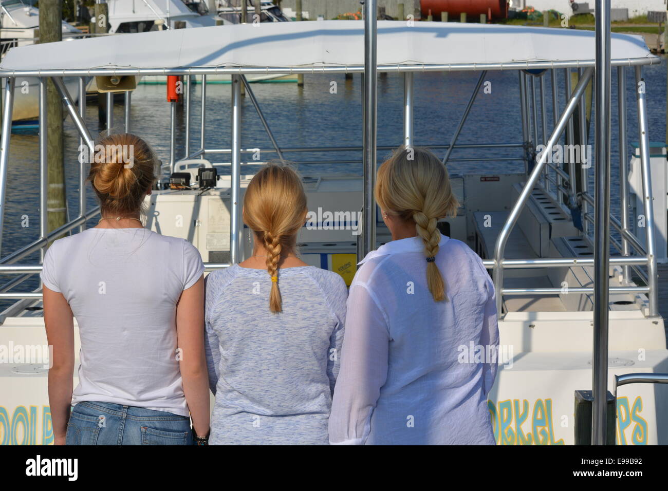 three women looking at boat, carefree hair styles Stock Photo