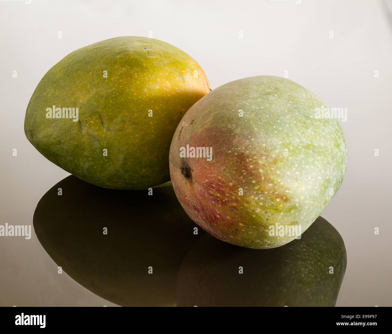 Two mangoes on reflecting surface Stock Photo