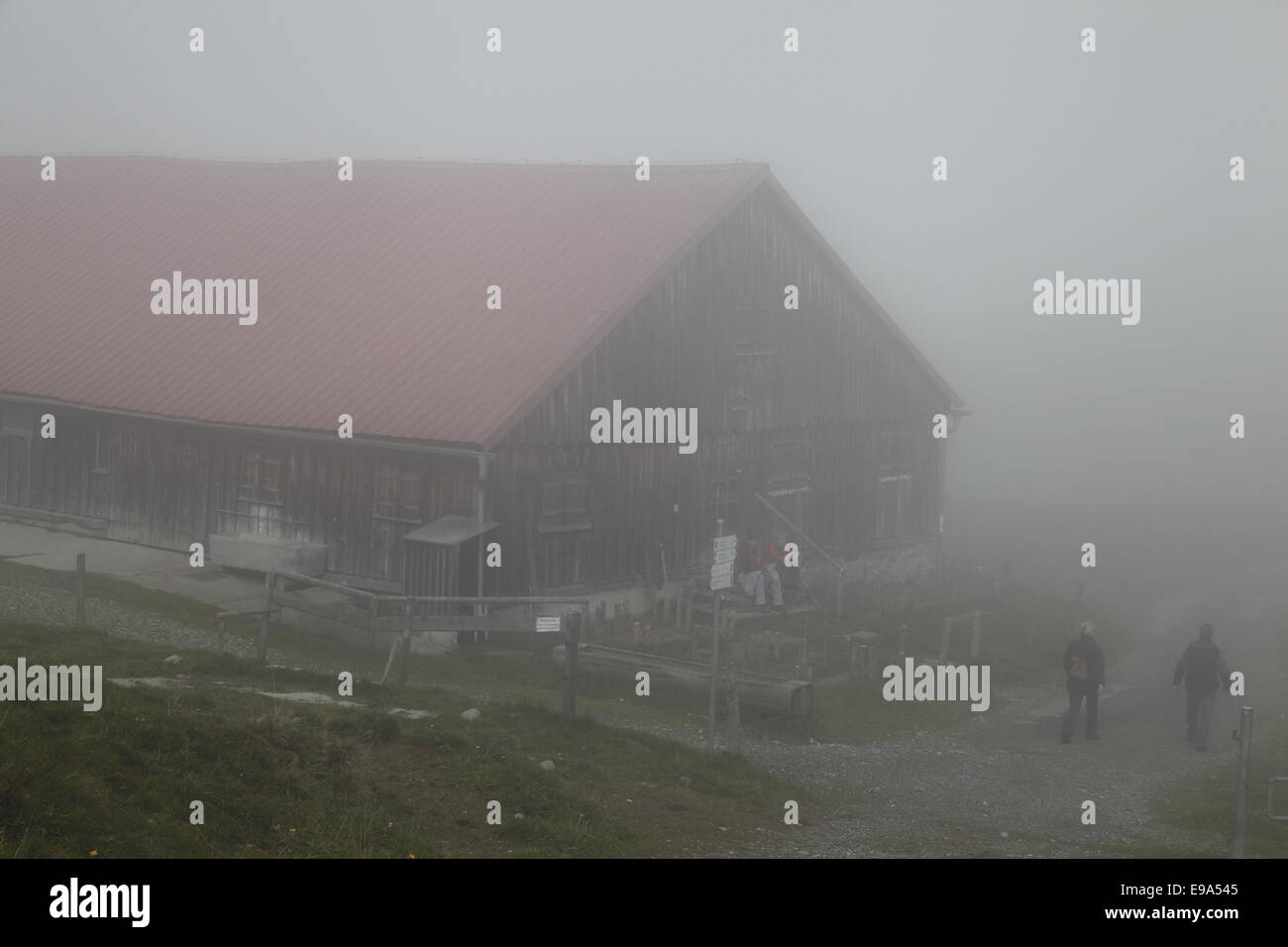 Alpine cabin in Fog with hiker Stock Photo