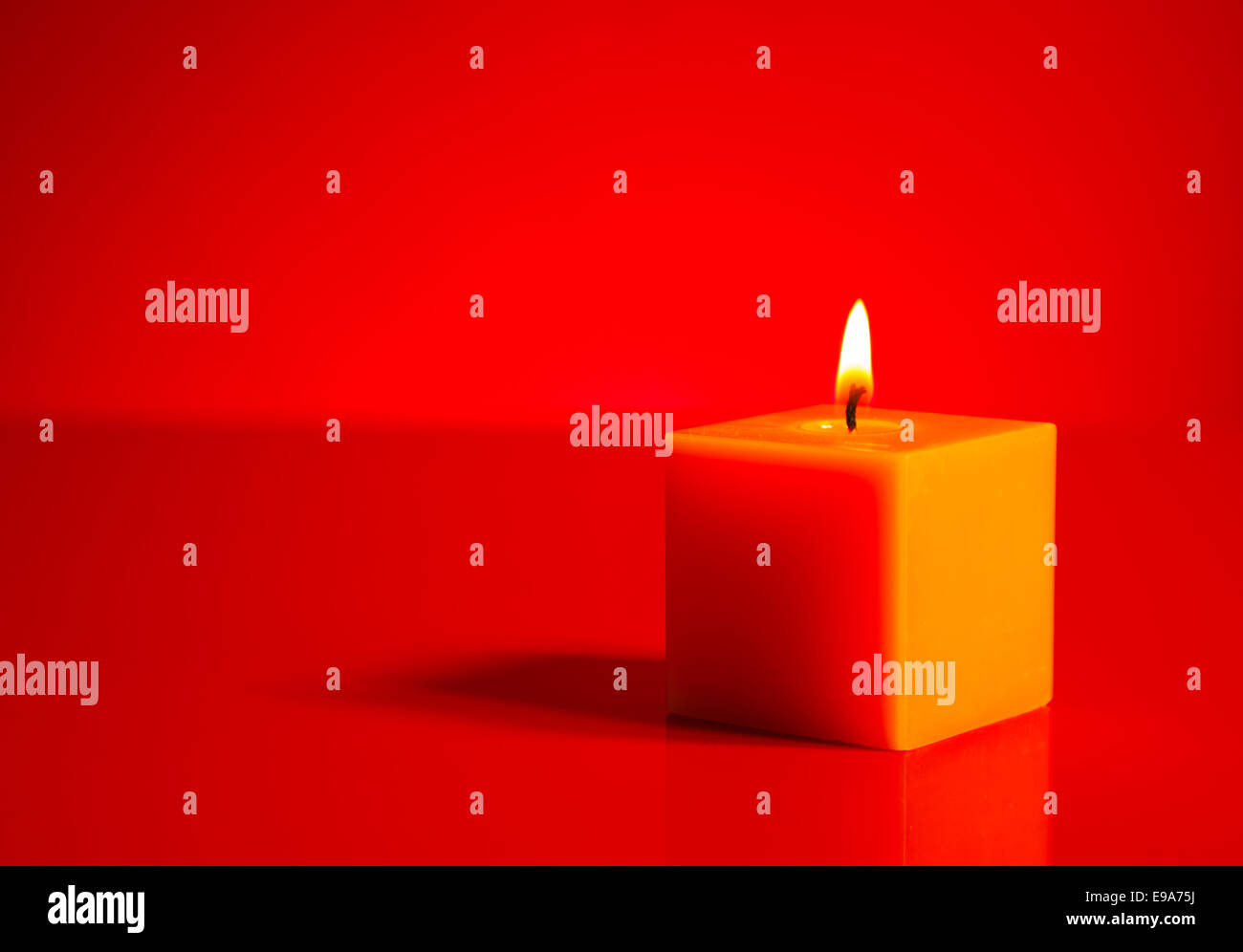 Burning yellow candle over red background Stock Photo Alamy