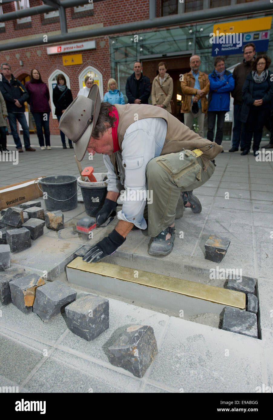 Stralsund, Germany. 23rd Oct, 2014. The artist Gunter Demnig places a tripping treshold at the main station in Stralsund, Germany, 23 October 2014. More than 1000 mentally ill people from the former regional mental institution were deported in 1939 via the main station. Altogether around 70 000 mentally ill people were victimised of the systematical holocaust campaign 'Aktion T4' during the National Socialism. Photo: Stefan Sauer/dpa/Alamy Live News Stock Photo