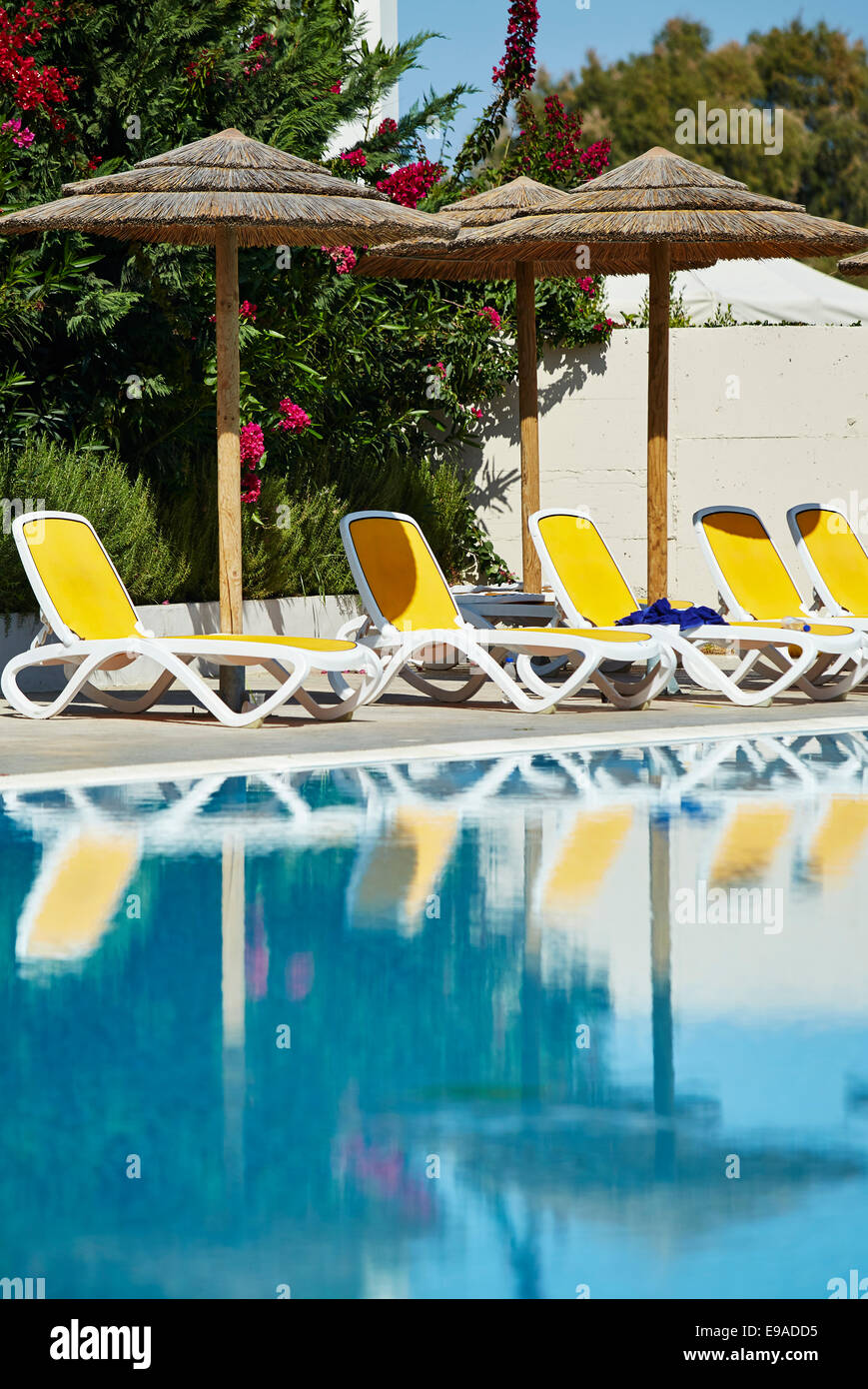 Empty sun loungers around swimming pool Stock Photo