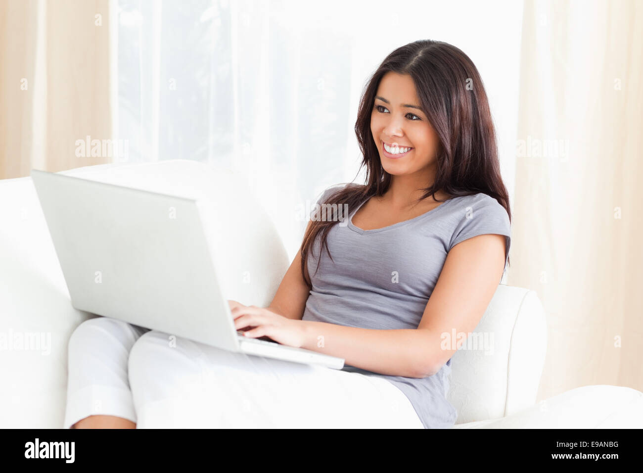 smiling woman sitting on sofa with laptop Stock Photo - Alamy