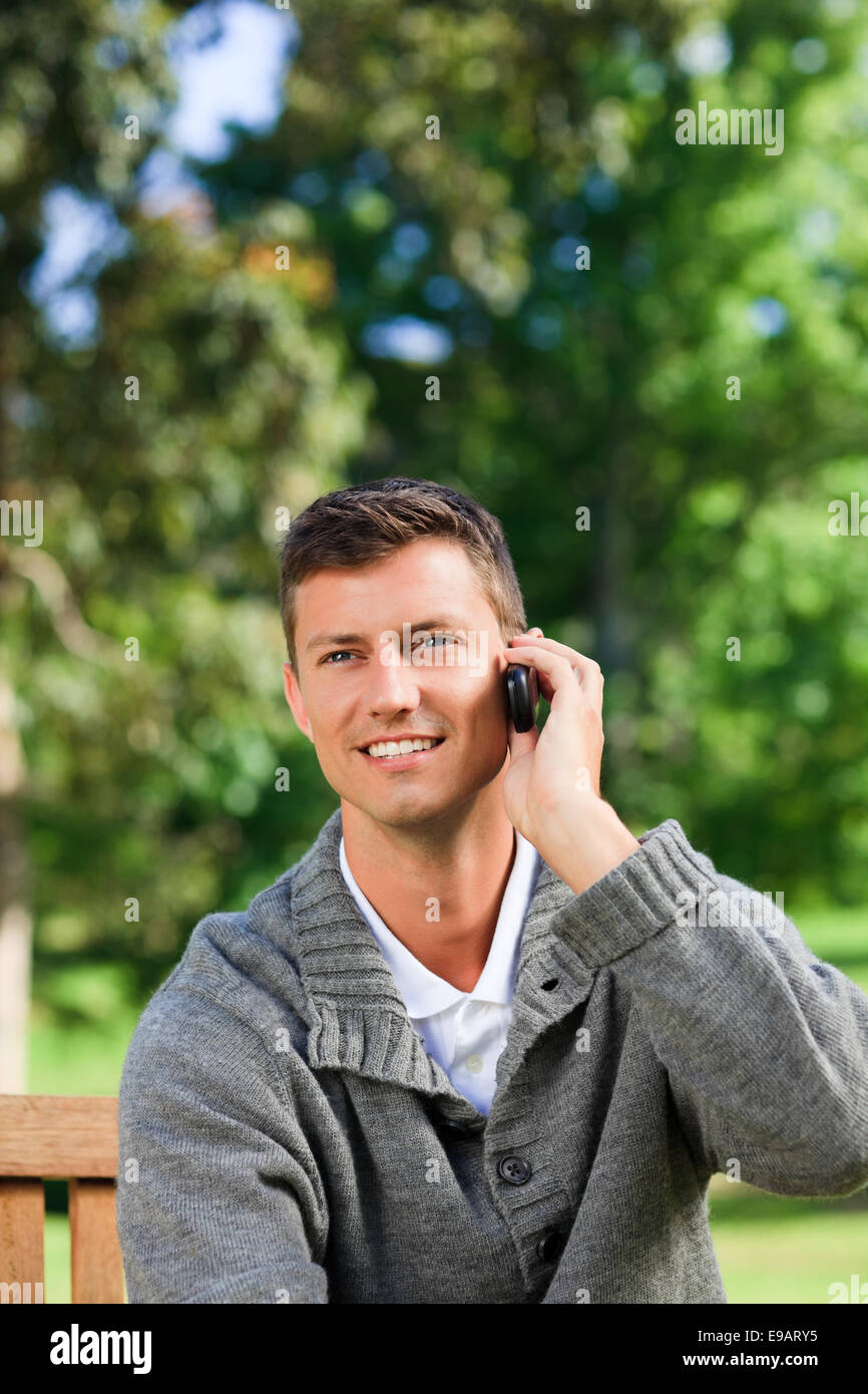 Young man phoning on the bench Stock Photo